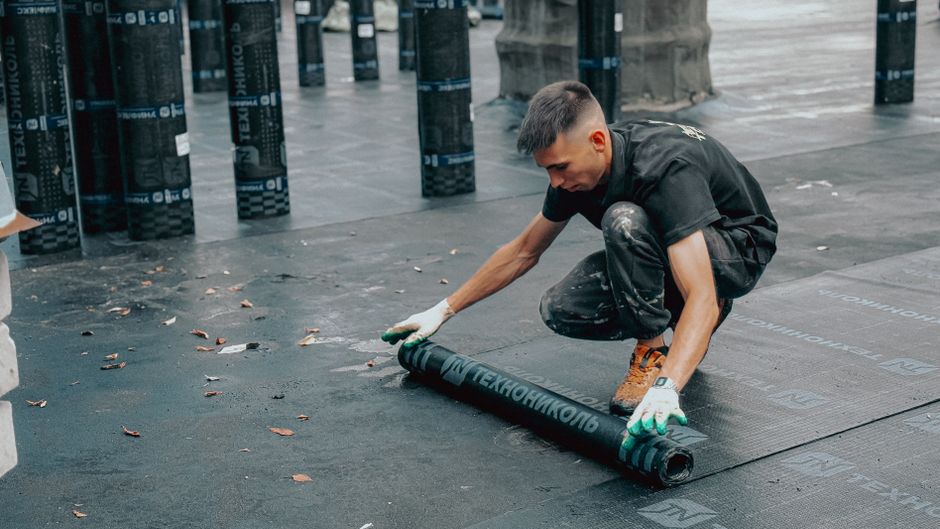 A worker applying a waterproof membrane to a flat roof