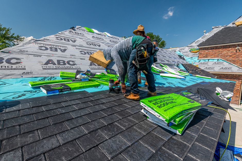 Roofers installing a slate roof on a brick house
